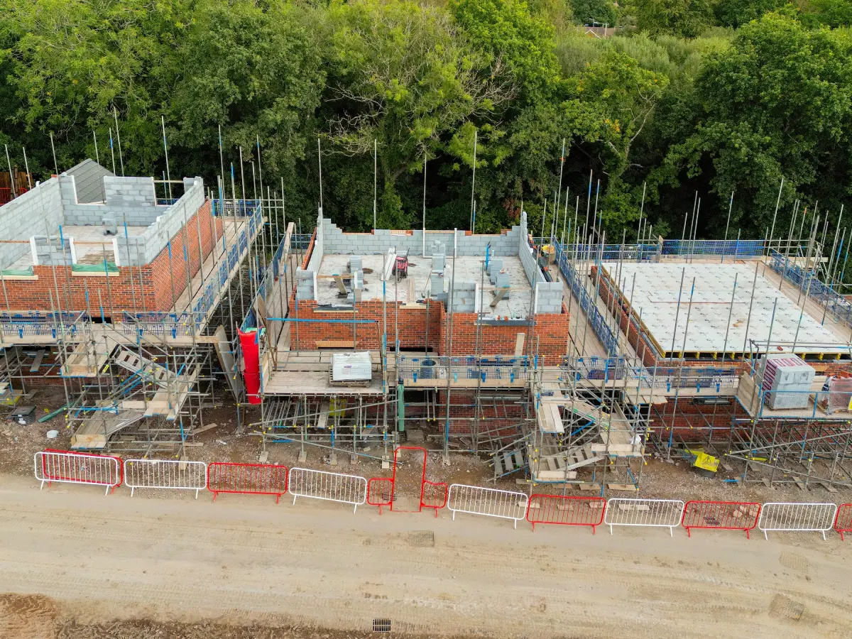 Vue aérienne d'un chantier de construction montrant d'importants échafaudages et engins de chantier, témoignant des travaux en cours.